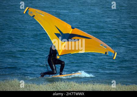 Persona que practica a la baja el viento en un papel de windsurf en el río Adur en Shoreham en marea alta. Foto de stock
