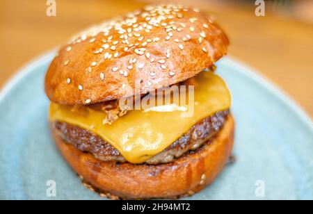 Hamburguesa de ternera artesanal con cheddar. Deliciosa hamburguesa de queso con cebolla crujiente en un plato. Foto de stock
