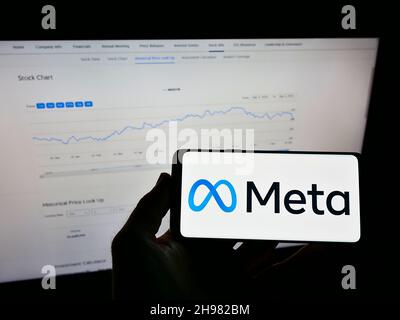 Persona que sostiene el teléfono móvil con el logotipo de la compañía estadounidense de tecnología Meta Platforms Inc. (Facebook) en pantalla con página web. Enfoque en la pantalla del teléfono.