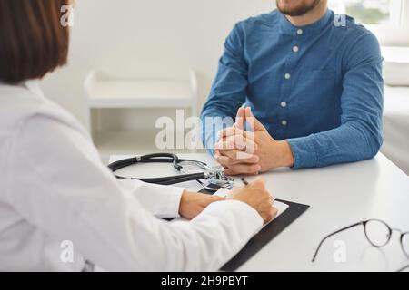Paciente conversando con un médico profesional sentado en la mesa de su oficina Foto de stock