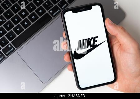 Logotipo de la aplicación Nike para realizar compras online en la pantalla del teléfono móvil. Hombre con la mano sosteniendo un smartphone con una aplicación. 2021 de noviembre, San Francisco, EE.UU Foto de stock