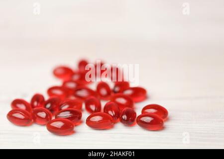Aceite de krill cápsulas de gelatina roja sobre fondo blanco de madera. Suplementos naturales y vitamina