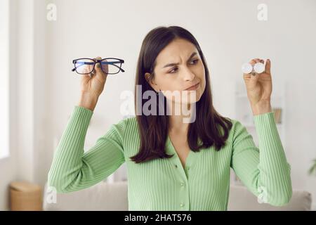Retrato de una mujer pensante que vacila en elegir entre gafas y lentes de contacto. Foto de stock