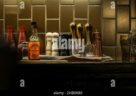 Accesorios de bar y restaurante, salsas y especias en el estante detrás del bar. Molinillos de sal y pimienta apilados en una bandeja lista para usar. Foto de stock