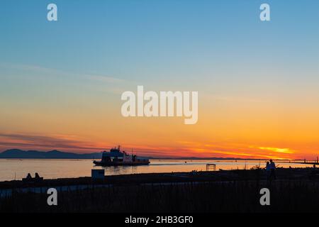 Barco en el mar pasando por la costa cerca de Richmond BC a la hora de la puesta del sol.