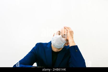 El hombre sostiene la cabeza con la mano izquierda y los ojos cerrados muestran el concepto de cansancio, negocios y frustración de los médicos. Foto de stock
