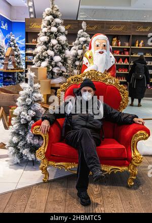 El anciano se sienta en silla con el árbol de navidad y el padre Chrisnas, Galeria Kaufhof, Alexanderplatz, Mitte, Berlín Foto de stock