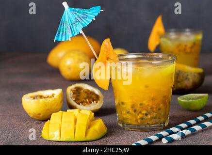 Jugo tropical de mango fresco, pasionfruit y lima en dos vasos sobre fondo oscuro Foto de stock