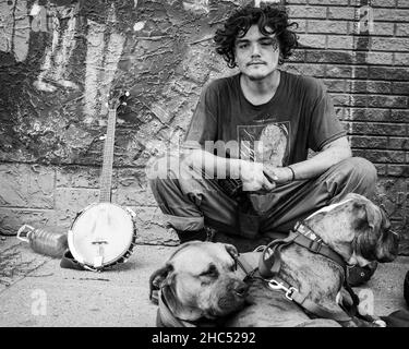 Disparo en escala de grises de un hombre sin hogar y su perro en una calle en Moose Jaw, Canadá Foto de stock