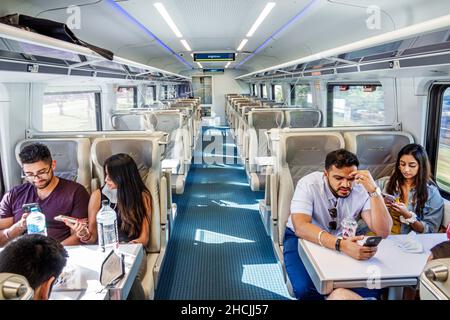 Miami Florida Brightline tren de pasajeros servicio de transporte de tren de tránsito masivo cabina de clase inteligente parejas hombres mujeres Oriente Medio asientos dentro de inte Foto de stock