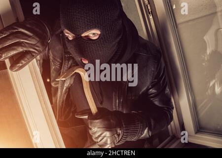 Ladrón con antifaz negro con una palanqueta para irrumpir en una casa por  la noche Fotografía de stock - Alamy