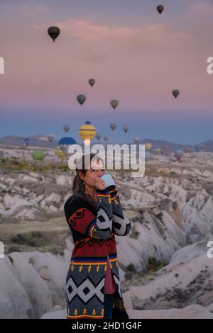 Mujer con chaqueta colorida con globos detrás al amanecer