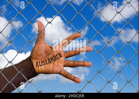 Die Hand eines Migranten hinter einem Maschendrahtzaun, Loch, Schlupfloch, Hilfe, Flüchtling, Asyl, Migrante, Migración, Ausländer, Schwarz, Afrikaner,