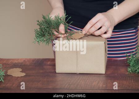 Manos de la mujer decorando regalos de Navidad y Año Nuevo durante las vacaciones en invierno Foto de stock