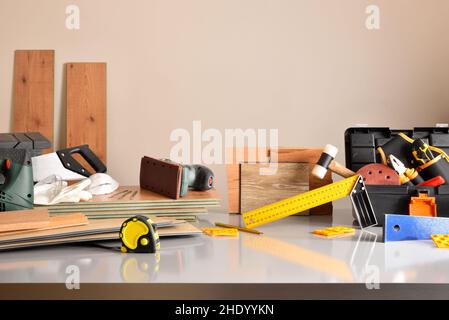 Exposición de materiales y herramientas para el montaje de parquet y palets de madera sobre una mesa en almacén. Composición horizontal. Foto de stock