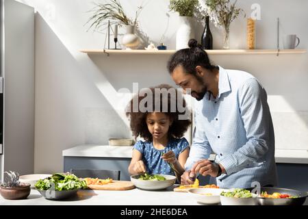 Dulce niña negra ayudando a papá a preparar la cena Foto de stock