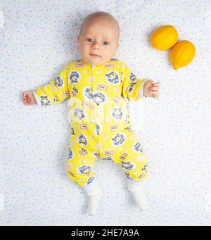 Novosibirsk, Rusia - 04. 01. 2021: Bebé recién nacido feliz sonriente de  dos meses en la ropa amarilla en la cama, infancia con 2 limones para  indicar la edad Fotografía de stock - Alamy