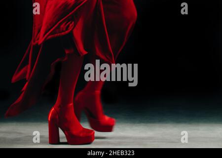 Modelo de moda en medias rojas, falda larga y tacones altos sedosos de diseño que caminan por la pista. Toma de moda