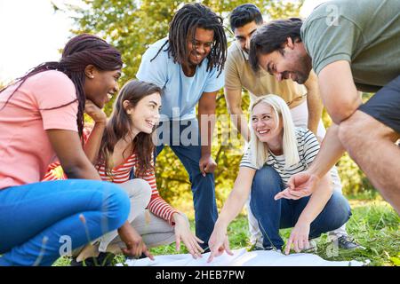 Feliz grupo de amigos jugando al juego del terreno con mapa en la naturaleza en verano Foto de stock