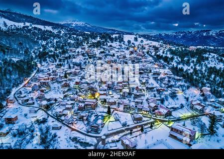 Cuando la noche cae sobre el pueblo nevado de Smixi, la montaña Vasilitsa, Grevena, Macedonia Occidental, Grecia. Foto de stock