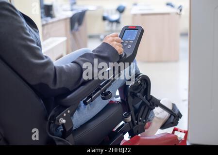 Primer plano de una mano femenina en el mango de control de una silla de ruedas eléctrica Foto de stock