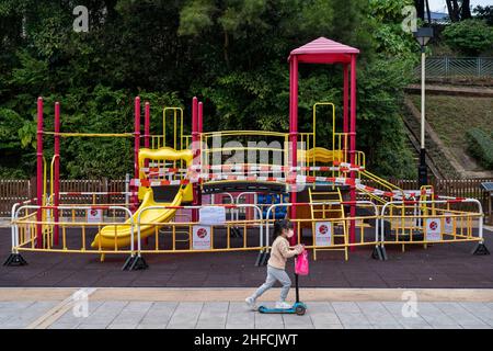 Hong Kong, China. 15th de Ene de 2022. Un niño viaja en un scooter eléctrico pasando por un patio cerrado en Hong Kong. El gobierno de Hong Kong reintrodujo restricciones sociales Covid más estrictas obligando a las empresas y lugares públicos a cerrar por lo menos después de las vacaciones y festividades del Año Nuevo Chino (CNY) para controlar la propagación de la variante de Omicra como el la estrategia del gobierno sigue orientada a la eliminación de las infecciones en la ciudad. Crédito: SOPA Images Limited/Alamy Live News