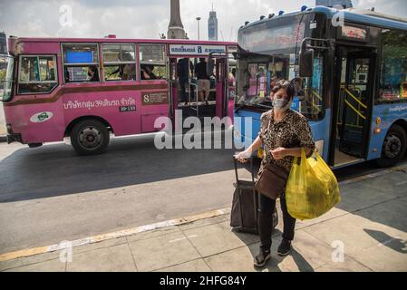 Bangkok, Tailandia. 16th de Ene de 2022. Una mujer que llevaba una máscara facial como medida preventiva contra la propagación del covid-19 vio jalar un equipaje en la parada de autobús del Monumento a la Victoria en Bangkok. Crédito: SOPA Images Limited/Alamy Live News Foto de stock