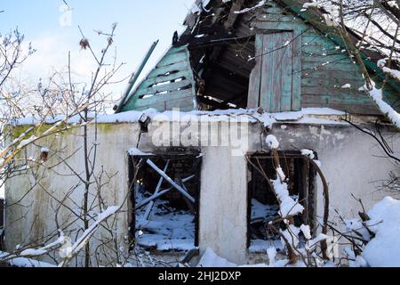 Antigua casa en ruinas en el pueblo en invierno. Nieve en el patio. Foto de stock
