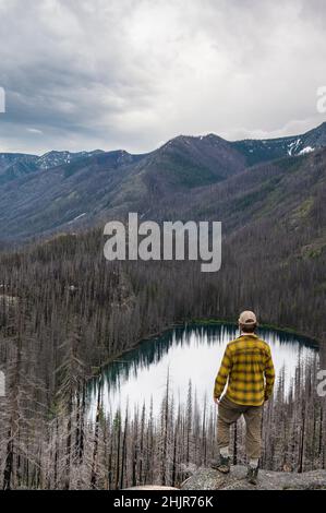 Male está sobre un lago alpino devastado por incendios forestales Foto de stock