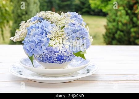 Floristería en wotk: Cómo hacer arreglos florales con flores de encaje  blanco de la reina Ana (daucus carota) y hortensia azul (hydrangea) sobre  ta de madera blanca Fotografía de stock - Alamy