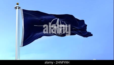 La bandera de la OTAN (Organización del Tratado del Atlántico del Norte) ondeando en el viento en un día claro. La OTAN es una alianza militar internacional que constituye un sistema Foto de stock