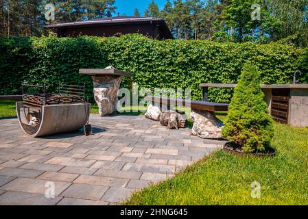 Fogata con bancos en pavimento de piedra en el patio trasero del jardín Foto de stock