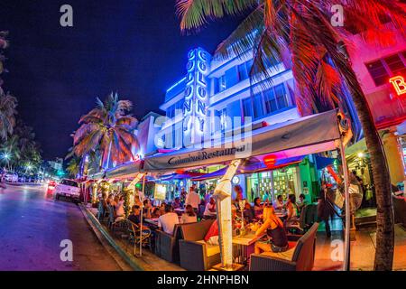 La gente disfruta de la noche en el restaurante Columbus al lado de la famosa colonia de hoteles art deco en Ocean Drive, Miami