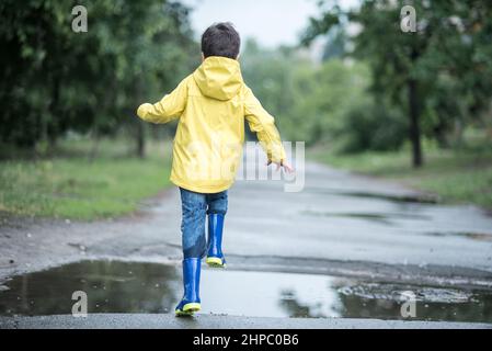 niño con capa impermeable amarilla, botas y paraguas jugando al aire libre  después de la lluvia 15290282 Foto de stock en Vecteezy