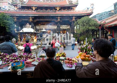 Gente que trae ofrendas al templo Bangka Lungshan, un templo budista en el distrito Wanhua de Taipei, Taiwán Foto de stock