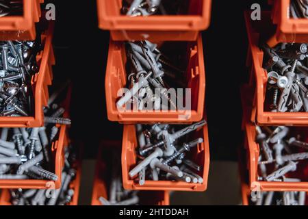 Cajas pequeñas con tornillos, tapones de pared y tuercas en un taller Foto de stock
