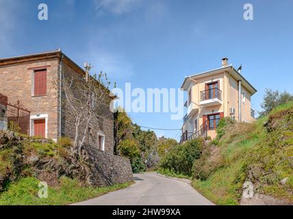 Dos casas al otro lado de la calle que entra en Afissos, un pequeño pueblo tradicional y complejo de verano construido en el lado sur del Monte Pelion, en Grecia. Foto de stock