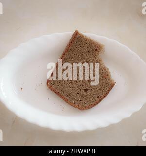 Trozo de pan de centeno semidesado sobre plato blanco Foto de stock