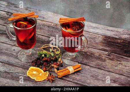 Dos vasos de vino caliente con especias y cítricos secos sobre una mesa de madera. Primer plano. Foto de stock