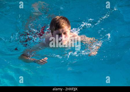 Jovencito goza de natación en la piscina Foto de stock