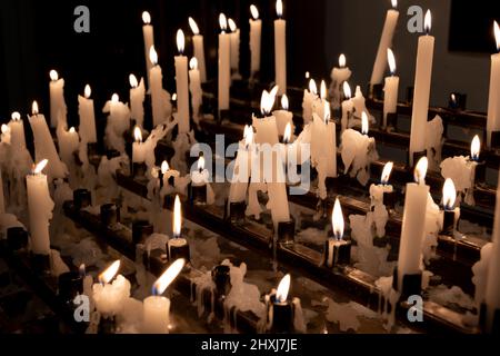 Velas votivas o candelas de oración encendidas en una iglesia, tradición cristiana. Foto de stock