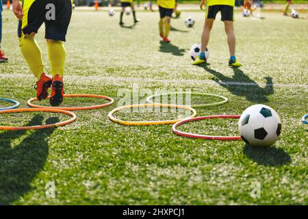Los jugadores de fútbol para niños se mueven prueba velocidad correr y saltar entre los aros hula para el entrenamiento de fútbol. de fútbol escolar en entrenamiento de