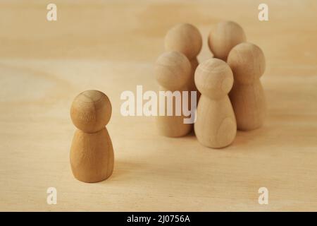 Peones de madera que representan a un grupo de personas en círculo y solo a la persona - concepto de racismo, exclusión social y aislamiento