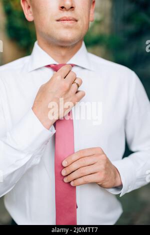 Kotor, Montenegro - 20.06.17: El novio en una camisa blanca endereza su corbata rosa. plano Fotografía de stock - Alamy
