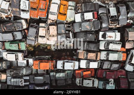 Vista aérea de un vertedero de automóviles soviéticos desde un avión de drone. Disparar desde arriba a montones de coches oxidados. Abandonados coches rusos a la espera de eliminación y..