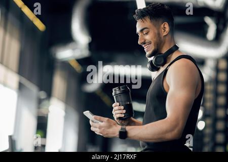 Hombre árabe joven deportivo con auriculares inalámbricos con smartphone en  el gimnasio Fotografía de stock - Alamy