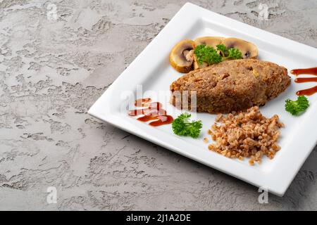 Cutlet con alforfón con setas en plato blanco
