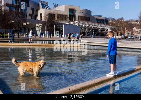 Edimburgo, Reino Unido. 27th Mar, 2022. En la foto: Los perros y los niños disfrutan del sol en las piscinas fuera del parlamento escocés. Crédito: Rico Dyson/Alamy Live News