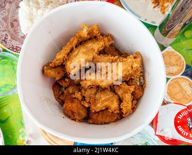 Trozos de pollo frito en una bañera sobre una mesa de comedor. Foto de stock
