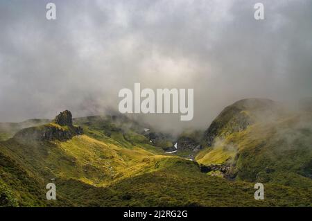 Las escarpadas gargantas alpinas y grietas del castillo de Humphries en el volcán Monte Taranaki (Nueva Zelanda) envuelto en nubes amenazantes. Foto de stock